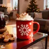 A festive Christmas scene with a mug of hot chocolate, gingerbread cookies, and a Christmas tree in the background. Produktbild-Vorschau