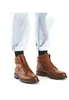 A pair of brown leather boots worn by a person with light blue jeans and black socks. Produktbild-Vorschau