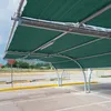 A dark green shade net structure providing sun protection over a parking lot. Náhľad obrázku produktu