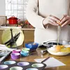 A person is baking in a kitchen, adding eggs to a bowl of ingredients. There are cupcake liners and a muffin tin on the table. Produktbild-Vorschau