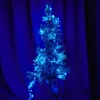 A small Christmas tree decorated with blue LED lights against a blue curtain background. Produktbild-Vorschau