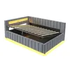A modern gray upholstered bed frame with an open slatted base and yellow LED lighting. Produktbild-Vorschau