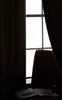 A dark room with a window and curtains, a chair, and an open book. Anteprima dell’immagine prodotto