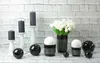 A collection of decorative items including candles, spheres, and a vase with flowers, arranged on a surface in front of a brick wall. Produktbild-Vorschau