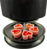 A close-up view of a black fondue pot heater with several heart-shaped red tea lights underneath. Produktbild-Vorschau