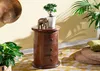 A wooden nightstand with drawers is decorated with a small plant and an elephant figurine, placed in a room with yellow walls and a patterned rug. Voir les images du produit