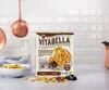 A box of Vitabella Haselnuss-Schoko-Kissen cereal is displayed on a kitchen counter, with a bowl of cereal and milk in the background. Anteprima dell’immagine prodotto