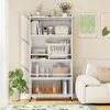 A white storage cabinet with multiple shelves and transparent doors, filled with books and decorative items, placed in a room next to a sofa and a plant. Náhľad obrázku produktu