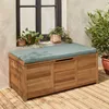 A wooden storage chest with a cushion on top, placed on a wooden deck next to a wall with plants on a windowsill. Anteprima dell’immagine prodotto