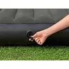 A hand is shown adjusting the valve on an inflatable mattress which is placed on grass. Náhled obrázku produktu