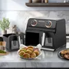 A black dual-chamber air fryer is shown on a kitchen counter, with a basket of fried food in the foreground. Produktbild-Vorschau
