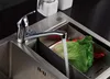A kitchen sink with a faucet running water into a colander containing vegetables. Produktbild-Vorschau