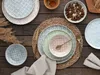 A table setting with multiple plates and cutlery on a wooden table. Produktbild-Vorschau