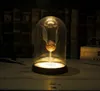 A golden snitch under a glass dome, illuminated from below, sits on a wooden table with books in the background. Podgląd zdjęcia produktu