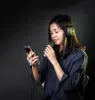 A young woman wearing headphones and holding a microphone and a smartphone. Anteprima dell’immagine prodotto