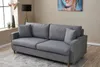 A grey sofa is shown in a living room setting with a painting on the wall and a floor lamp. Produktbild-Vorschau