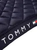 A close-up view of a quilted navy blue saddle pad with a Tommy Hilfiger branded ribbon. Produktbild-Vorschau