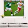 Two soccer players in action on a green field, with a projector screen displaying the image above a white entertainment center. Produktbild-Vorschau