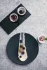 A beautifully plated dish with fish, berries, and a creamy sauce, served on a dark slate plate, with small bowls of truffles and herbs in the background. Podgląd zdjęcia produktu