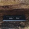 A close-up shot of a black USB hub embedded in a wooden surface. Voir les images du produit