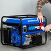 A person is plugging a cable into a blue generator. Produktbild-Vorschau