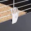 A close-up view of a white plastic clip attached to the wire bars of a pet cage. Podgląd zdjęcia produktu
