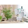 A sewing machine on a wooden table with fabric and spools of thread. Produktbild-Vorschau