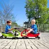 Two young children are playing on colorful ride-on toys outdoors on a sunny day. Náhled obrázku produktu