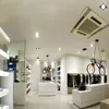 A modern retail store interior with clothing displays and unique bicycle-shaped pendant lights. Podgląd zdjęcia produktu