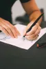 A person's hands are shown writing on a piece of paper with a fountain pen. Produktbild-Vorschau