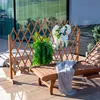 A wooden garden screen with plants and flowers on a patio with a lounge chair. Podgląd zdjęcia produktu