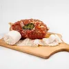 A raw meat product wrapped in netting, placed on a wooden cutting board with additional netting material. Produktbild-Vorschau