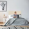 A young boy sits on a bed in a bedroom. Produktbild-Vorschau