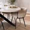 A dining chair with a textured beige upholstery is placed next to a light-colored oval dining table, set with plates and glasses. Produktbild-Vorschau