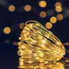 A close-up of a coiled string of warm white LED lights with a dark, bokeh background. Produktbild-Vorschau