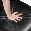 A hand pressing into a black, cushioned surface, likely a chair or sofa cushion. Produktbild-Vorschau