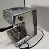 A silver espresso machine on a white surface with a gray background. Produktbild-Vorschau