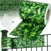 A roll of green leaf-patterned fence screening is shown, along with a section of installed screening on a fence and some mounting clips. Náhled obrázku produktu