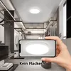 A hand holding a smartphone displaying a ceiling light in a modern closet. Produktbild-Vorschau
