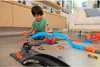 A young boy is playing with a Hot Wheels track set in a living room. Voir les images du produit