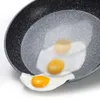 A close-up shot of a frying pan with two fried eggs in it and one partially out of the pan. Anteprima dell’immagine prodotto