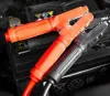 A close-up shot of red and black jumper cable clamps resting on a car battery. Podgląd zdjęcia produktu