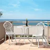 A white metal bistro set for two with a bottle of wine and two glasses on a balcony overlooking the ocean. Produktbild-Vorschau