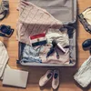 An open suitcase filled with travel items, including clothes, a camera, a hairdryer, and an Egyptian flag. Produktbild-Vorschau