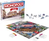 A Monopoly board game box and board are displayed with game pieces. Produktbild-Vorschau