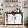 A white buffet cabinet with sliding barn doors and drawers, styled in a kitchen or dining room setting with decorative items and plants. Voir les images du produit