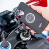 A hand holding a smartphone case over a motorcycle mount. Podgląd zdjęcia produktu
