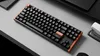 A mechanical keyboard is placed on a desk next to a stapler. Podgląd zdjęcia produktu