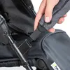 A hand is shown connecting a strap to a stroller. Produktbild-Vorschau
