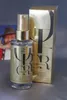 A bottle of Wella Oil Reflections Luminous Smoothing Oil and its packaging are displayed on a gray surface. A blurred image of a person wearing a hat is visible in the background. Produktbild-Vorschau